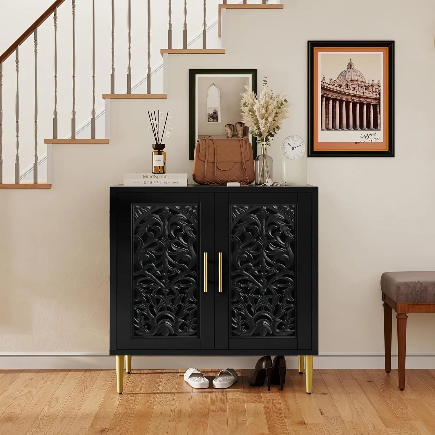 Decorative black cabinet with gold legs in a home setting with staircase and wall art.