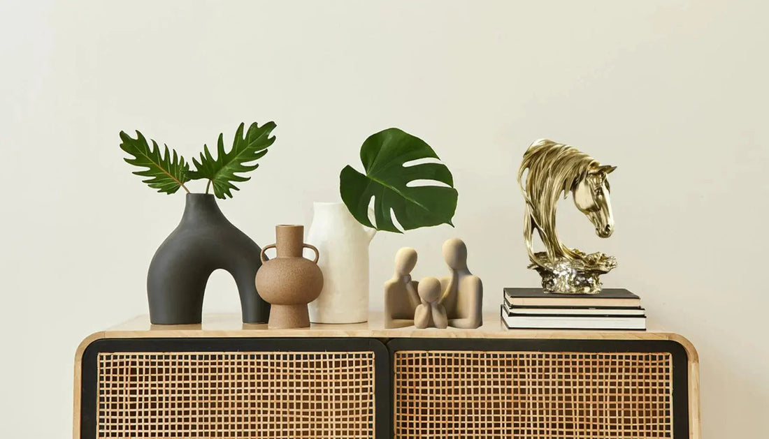 Modern rattan cabinet with ceramic vases, green leaves, abstract sculptures, and gold horse decor