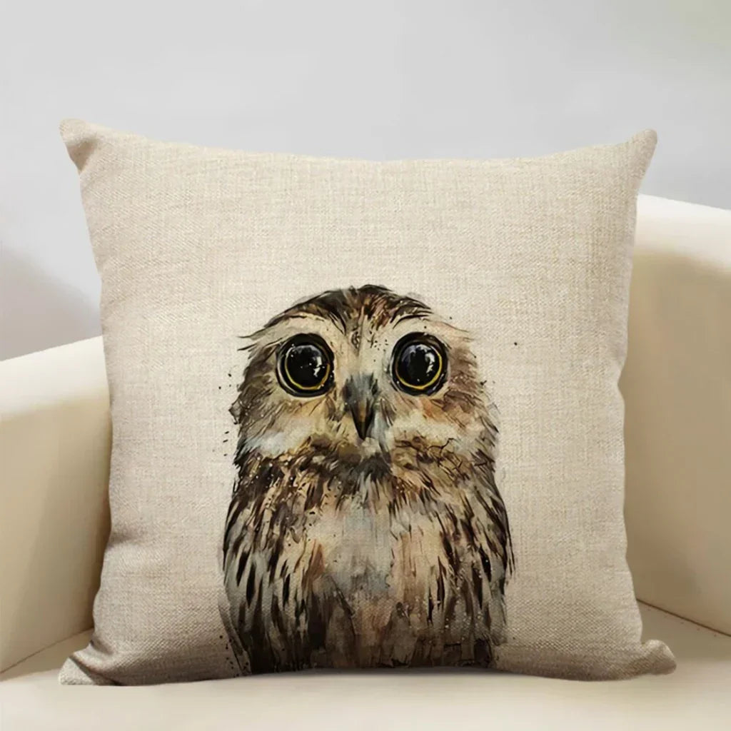Decorative beige cushion with large-eyed owl watercolor print on white armchair