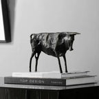 Black matte-finished bronze bull statue with metallic finish standing on stacked books for home decor display