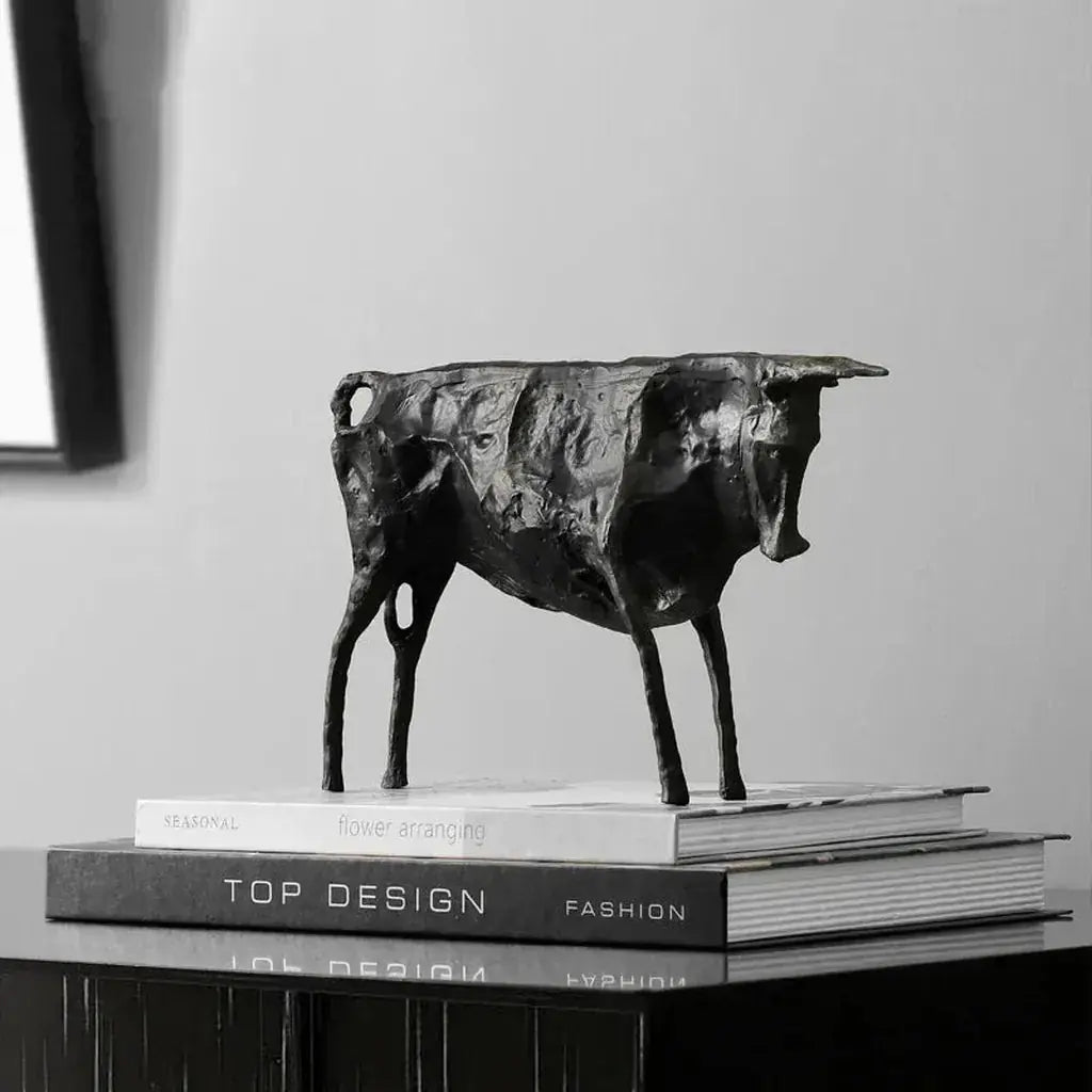 Black matte-finished bronze bull statue with metallic finish standing on stacked books for home decor display