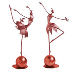 Two rose-gold abstract dancing ballerina metal sculptures on polished spherical bases, one balancing and one with a bird