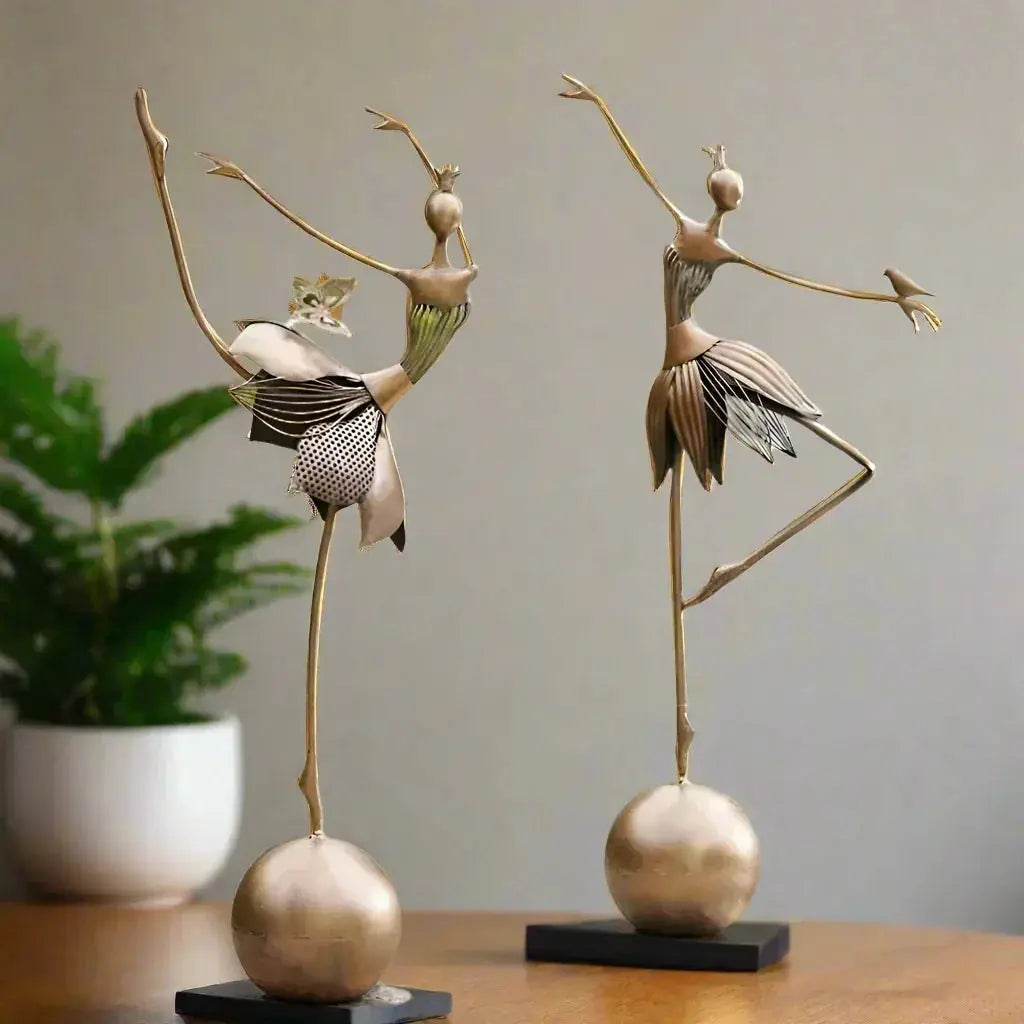 Two elegant gold-toned abstract dancing ballerina metal sculptures with layered patterned fabric skirts