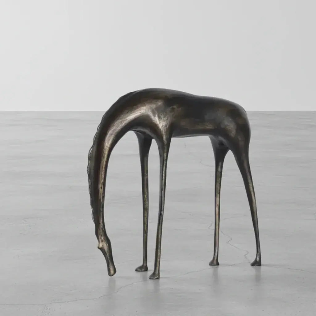 Abstract bronze giraffe sculpture with elongated legs and neck resembling an abstract grazing horse sculpture for decor