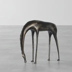 Abstract bronze giraffe sculpture with elongated legs and neck resembling an abstract grazing horse sculpture for decor