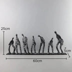 A sleek matte black abstract metal figure sculpture of seven stylized human forms in dynamic poses on a flat base