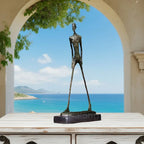 Bronze abstract walking man sculpture with elongated limbs and textured metal surface on dark rectangular base