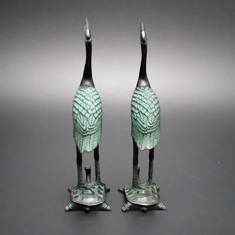 Pair of bronze-colored antique crane figurines with green patina standing on detailed turtle statue bases for luxury decor