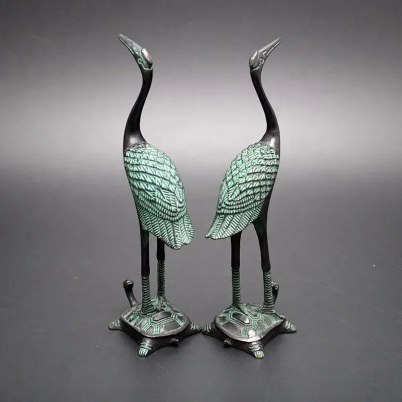Pair of bronze-colored antique crane figurines with green patina standing on detailed turtle statue bases for décor