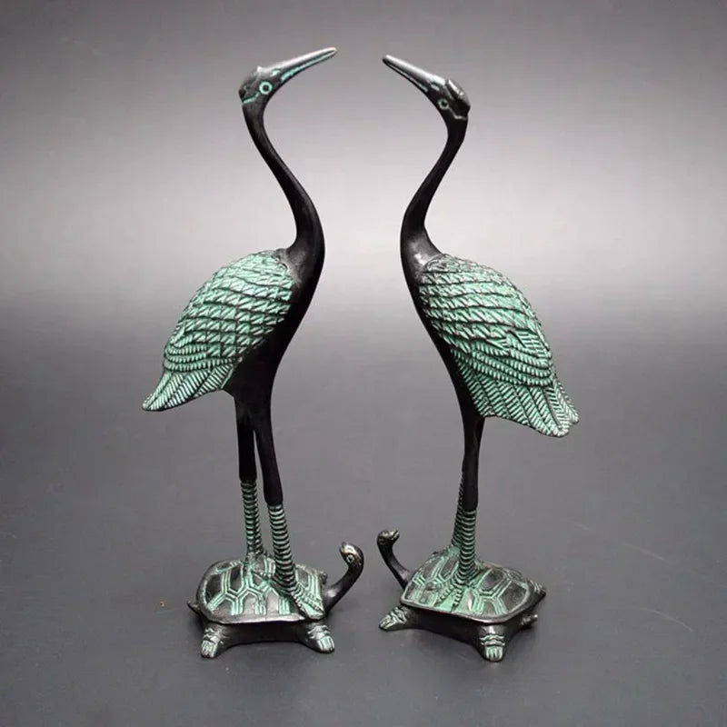 Pair of bronze-colored antique crane figurines with green patina standing on turtle statue bases for luxury decor