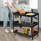 Person pushing a black three-tier cart filled with food and drinks in a kitchen.