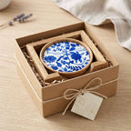 Blue and white ceramic coaster in a brown box with a decorative tag on a wooden surface. [[SKU:HOA-MOR-KIT-007]]
