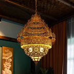 Ornate gold chandelier hanging in a room with decorative elements.