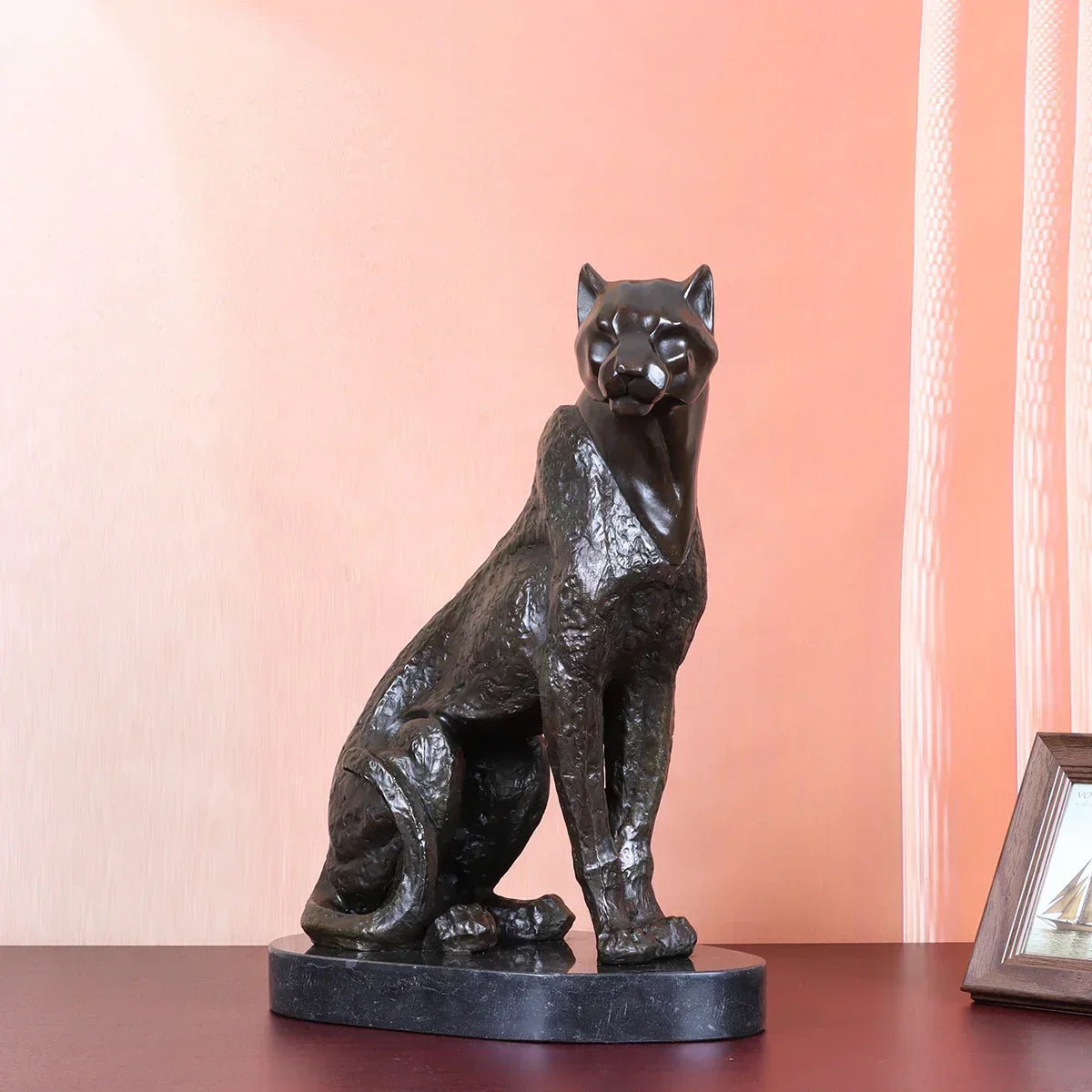 Bronze cheetah decorative sculpture in black bronze with detailed fur texture seated on dark marble base for living rooms