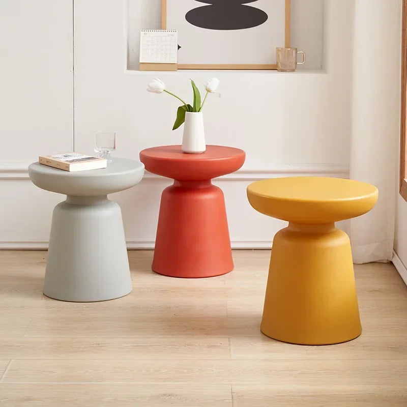 Three modern minimalist stools in matte gray coral red and mustard yellow complement a compact size coffee table for living room use