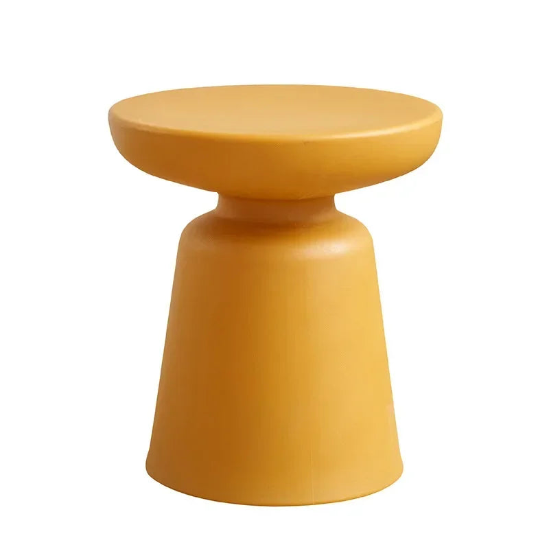 A sleek mustard-yellow resin coffee table with compact size featuring a rounded top and tapered base for living room use