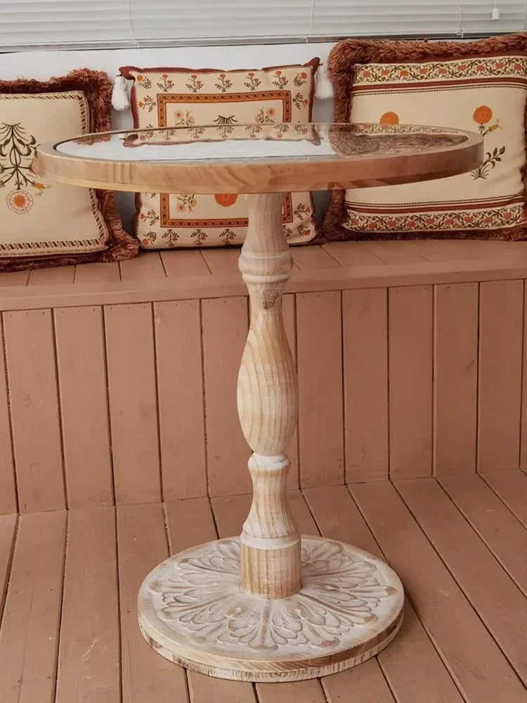 Coffee table small round wooden with a glass top and ornate carved base in natural wood finish