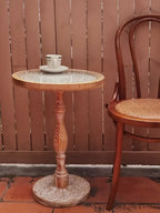 Small round wooden coffee table with a light carved top and intricately detailed pedestal base for elegant decor