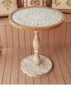Small round wooden coffee table with white intricately carved mandala patterned top and matching ornate base