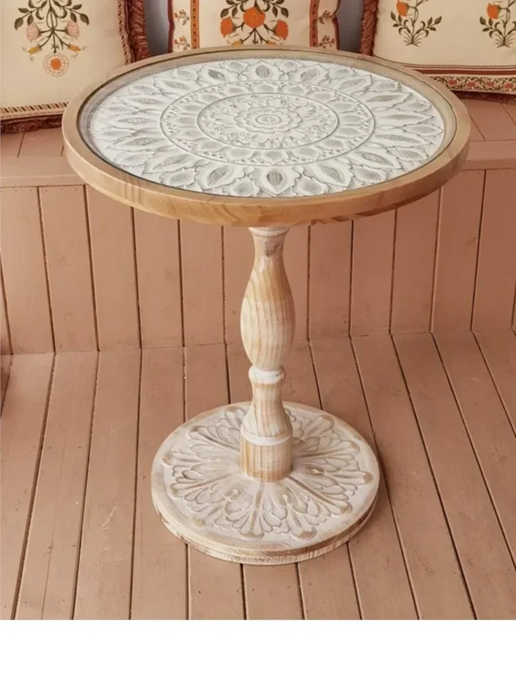 Small round wooden coffee table with white intricately carved mandala patterned top and matching ornate base