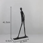 A sleek dark gray metallic desk statue with a slender humanoid figure in modern design for home office use