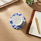 Teacup with saucer, notebook, pen, and glasses on a wooden surface [[SKU:HOA-MOR-KIT-007]]