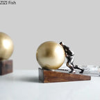 Bronze-colored fitness figure statue in modern style pushing a golden sphere on wooden base for home decor