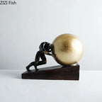 Black metal figure statue of a man pushing a golden sphere on a dark wooden base modern style home decor