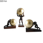 Set of three bronze-finished modern style figure statues with golden spheres on dark wood bases for home decor
