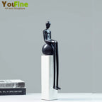 Black minimalist luxury metal small figurine of a seated figure with elongated limbs on a glossy sphere pedestal