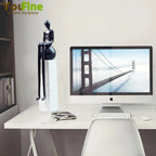 Black glossy luxury metal small figurine of a seated humanoid with elongated limbs on a white pedestal