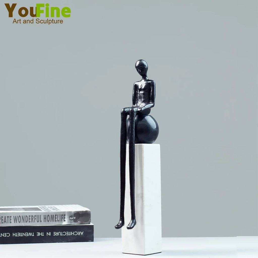 Black glossy resin figurine luxury metal small sculpture with elongated limbs seated on a spherical metal small base
