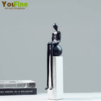 Black glossy resin figurine luxury metal small sculpture with elongated limbs seated on a spherical metal small base