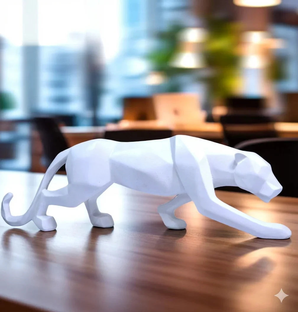 White panther sculpture on a wooden surface with a blurred indoor background