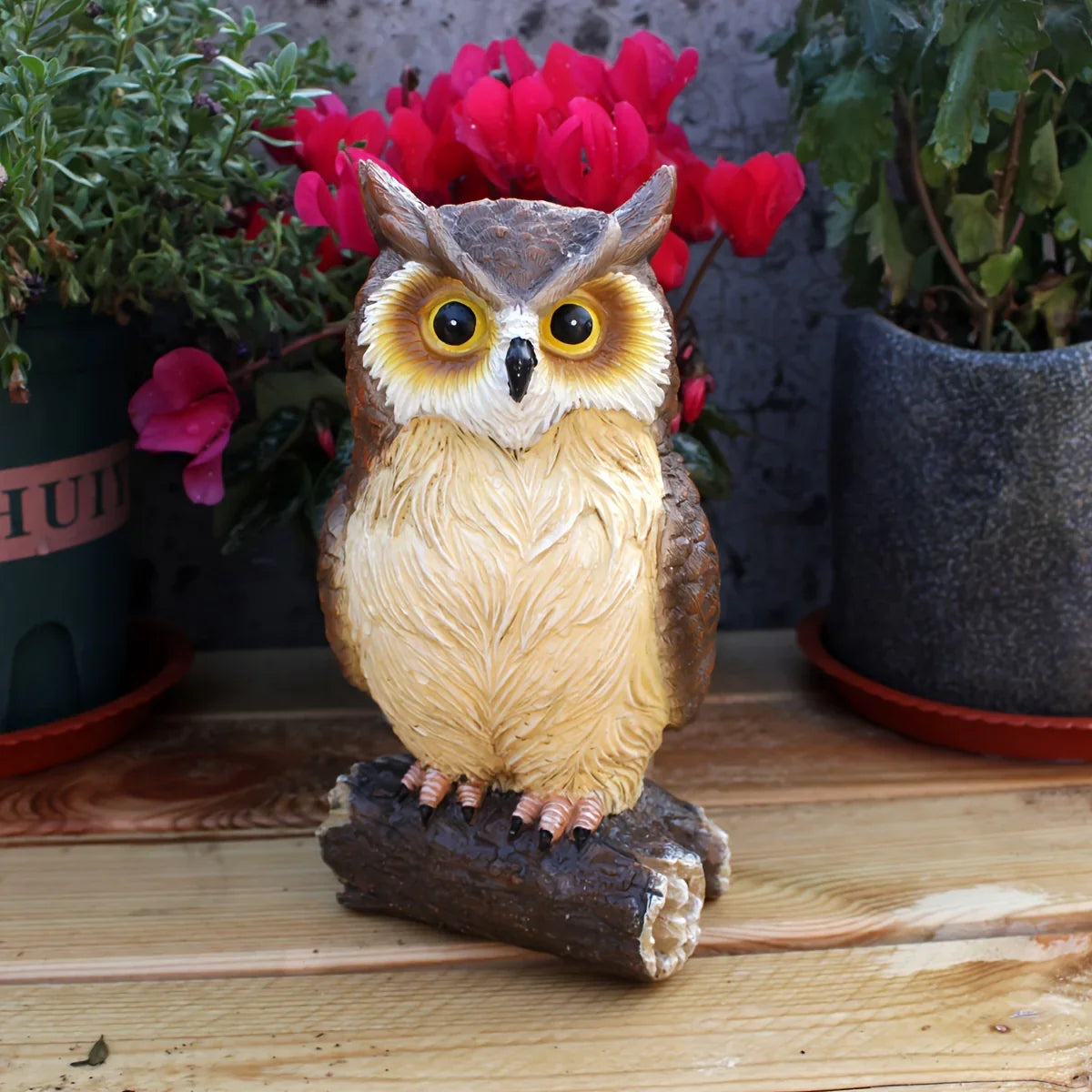 Handcrafted owl statue with realistic feather details perched on a log in a garden setting.