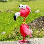 Handcrafted red metal flamingo garden sculpture with large eyes standing in a green garden.