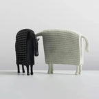 Two stylized ceramic sheep figurines in black ridged and white woven mesh textures complement an elegant horse figurine