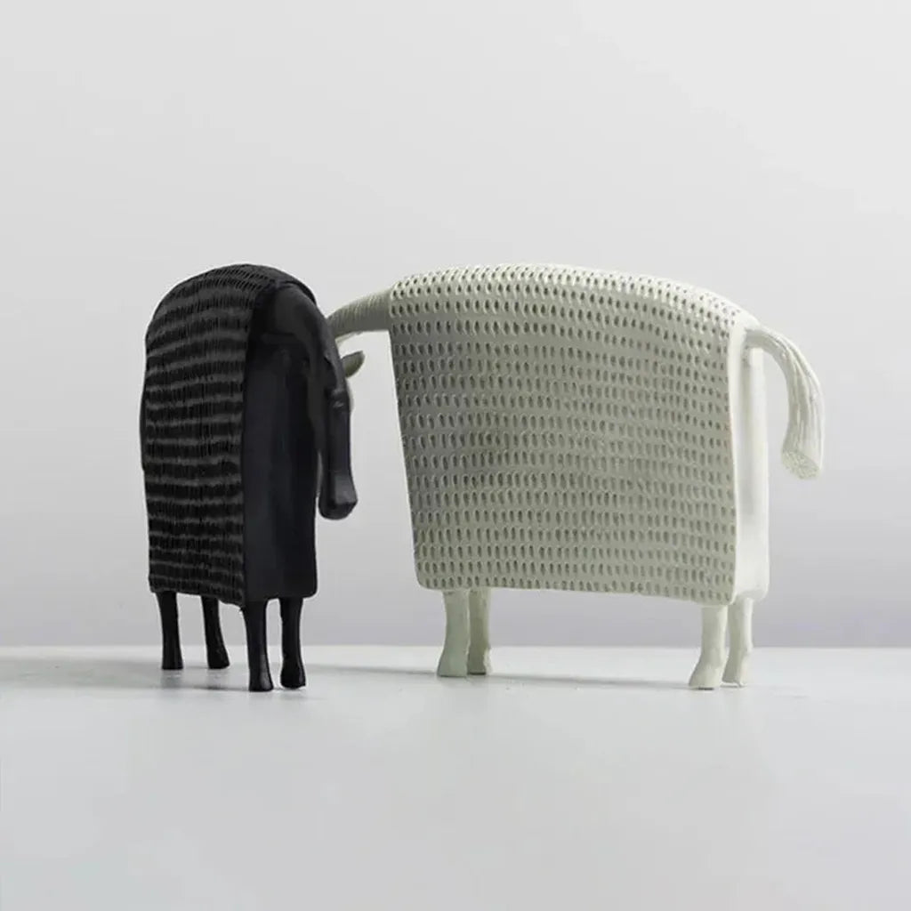 Two stylized ceramic sheep figurines in black ridged and white woven mesh textures complement an elegant horse figurine