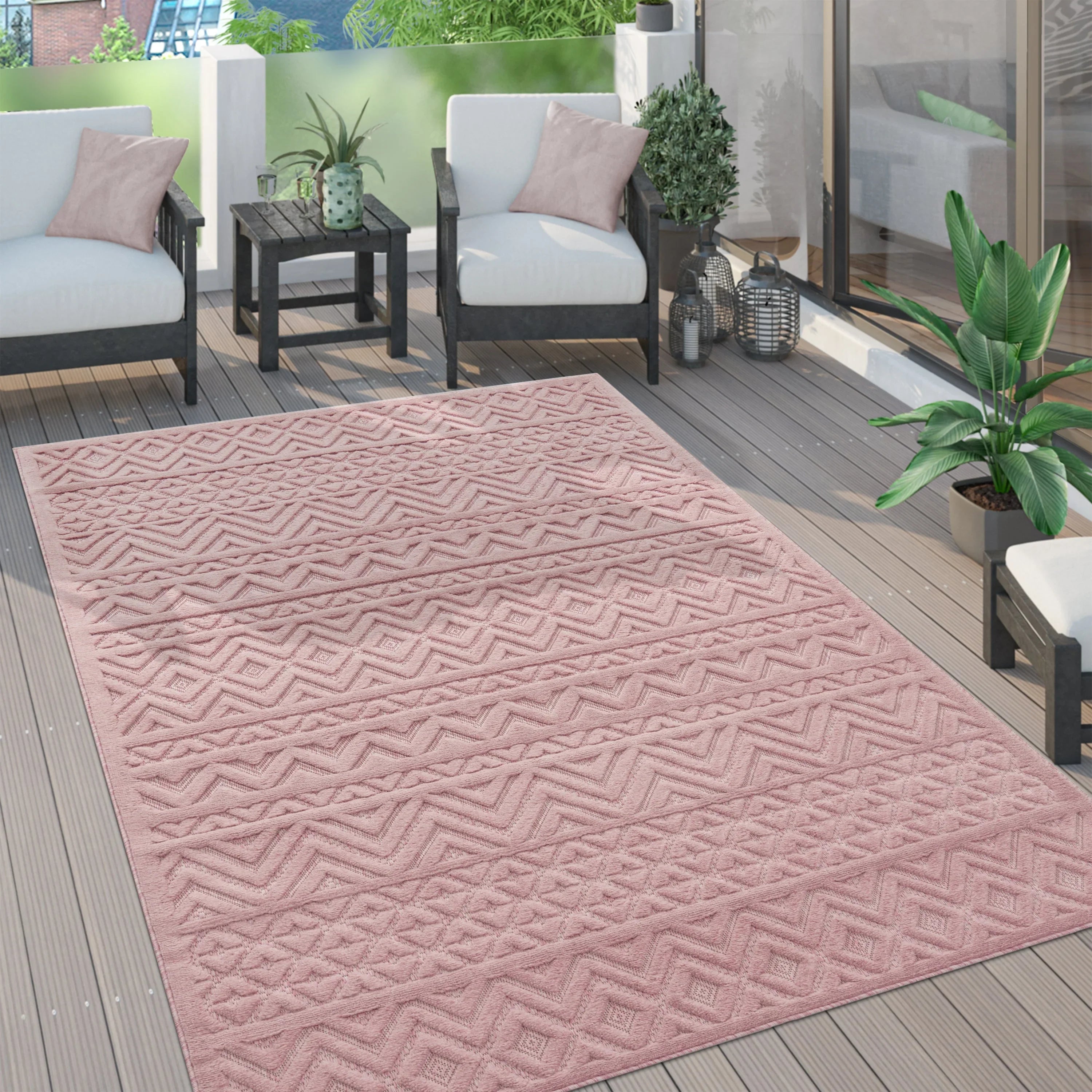 Pink boho style rug with a geometric high-low pattern on a modern wooden patio deck.
