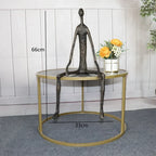 Large abstract sitting human sculpture in dark bronze with elongated limbs on a circular gold metal table