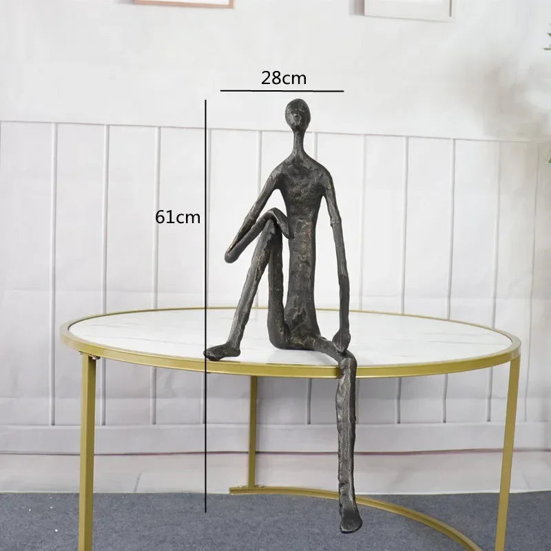 Large abstract sitting human sculpture in dark metal with elongated limbs on round table modern figurine design