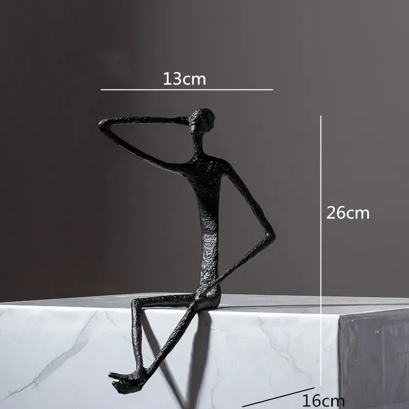 Large abstract sitting human sculpture in black textured metal with one arm raised in a modern sitting pose