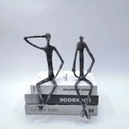 Two large abstract sitting black metal figurines textured sitting human sculpture on a stack of books