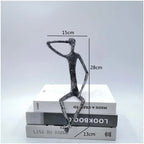 A sleek large abstract sitting human sculpture in modern metal with one arm raised to its head