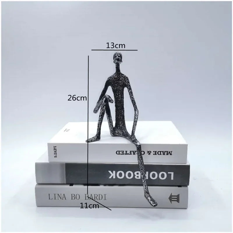 A large abstract sitting human sculpture in sleek black metal with elongated limbs and textured surface design