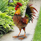 Colorful large rustic metal chicken garden stake with a red comb and patterned body in a lush garden setting.