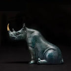 Luxury sitting rhinoceros animal figurine in antique green bronze with gold-colored horn details for decorative display