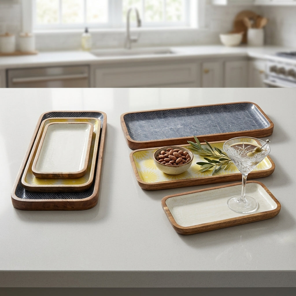 A set of rectangular ceramic serving trays with warm wood-look rims, displayed on a white kitchen countertop with a blurred kitchen background. The trays feature cream, yellow, and textured dark gray glazes.
