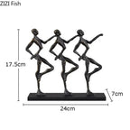 Black metallic metal sculpture of three stylized dancers on a rectangular base for a unique metal desk accessory