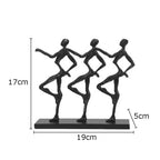 Black metallic unique metal sculpture depicting three abstract dancers on a rectangular base for a unique metal desk